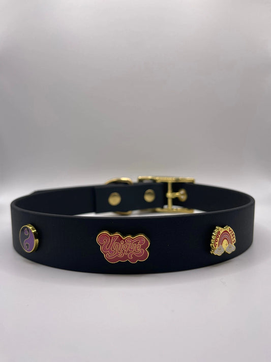 Black dog collar with colorful enamel pins on a gray background