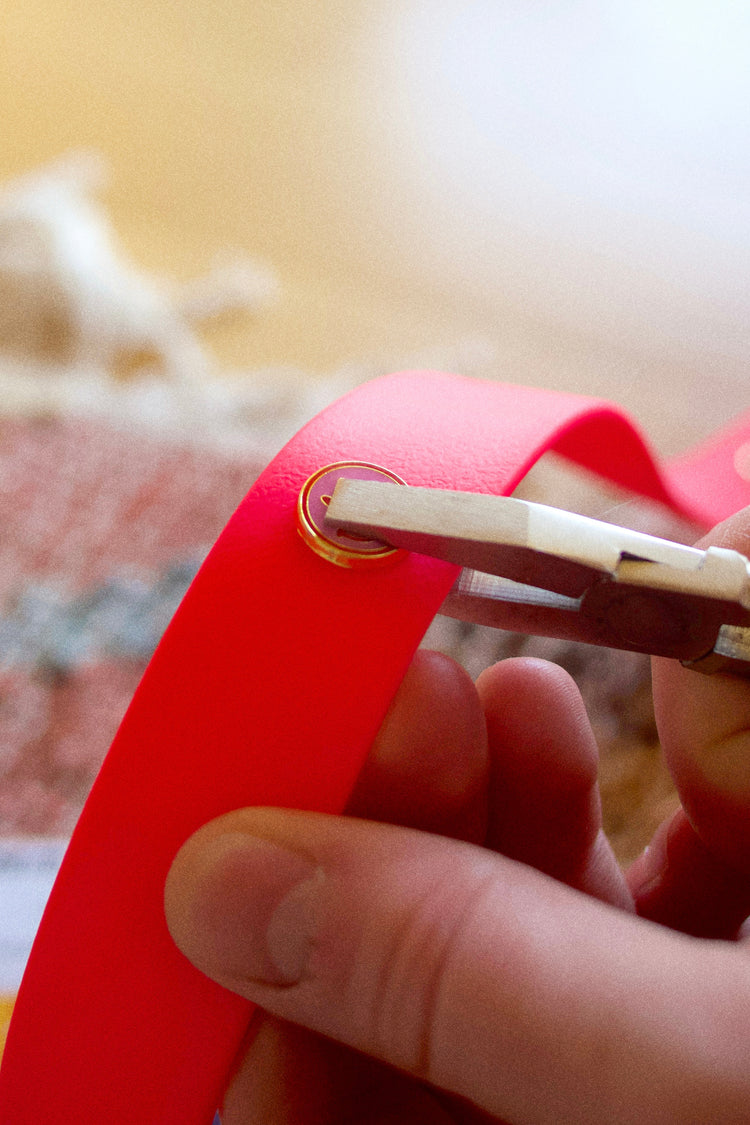 fixing with tongs a pins on a pink dog collar