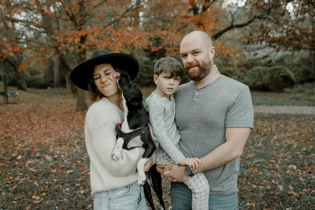 Botanical bones brand creator with a dog licking the voman's face and a child carried by his dad