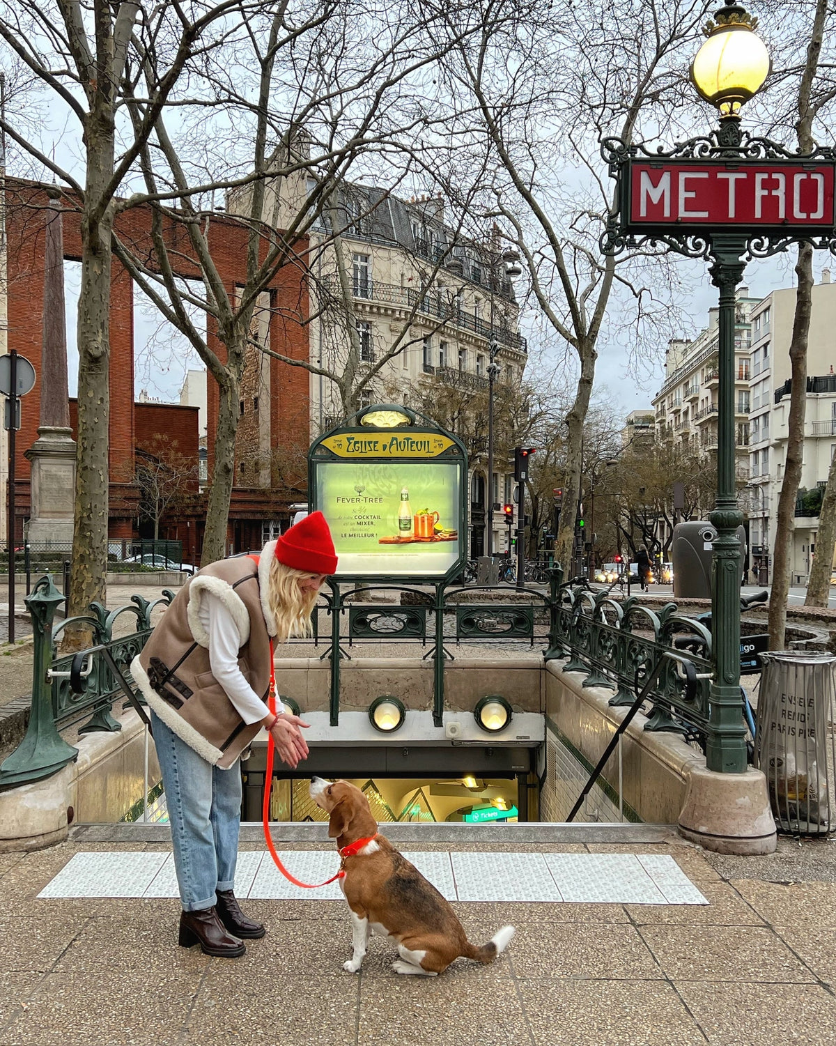 Woman with a dog in an urban setting with a parisien metro sign in the background